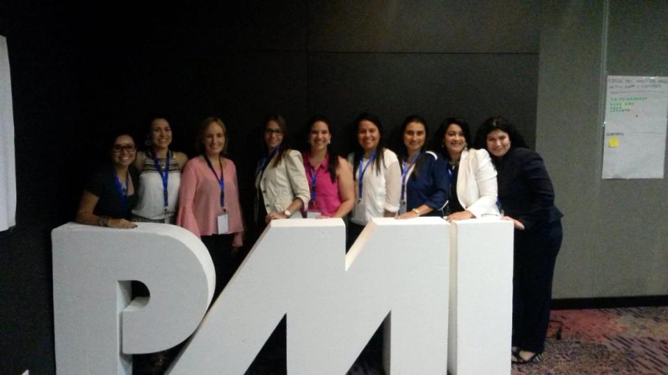 Equipo frente a las letras del PMI en un evento del Project Management Institute