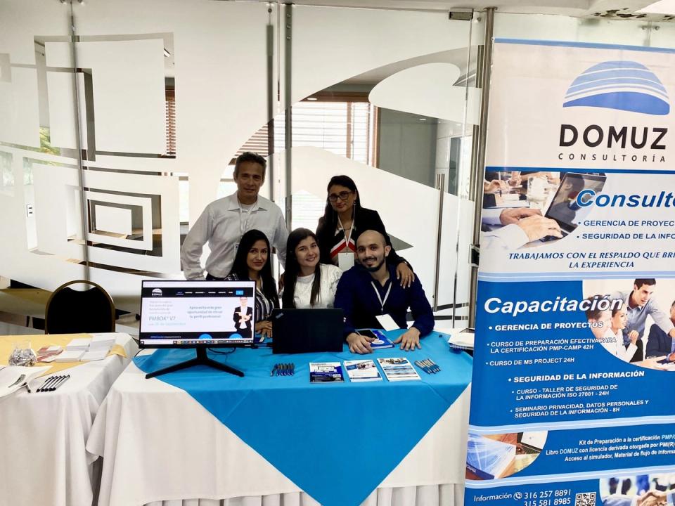 Equipo de DOMUZ atiende su stand con pendón y material informativo en un evento empresarial