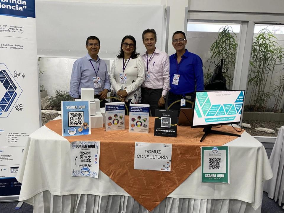 Stand de DOMUZ Consultoría con pantalla, códigos QR y material impreso en un evento