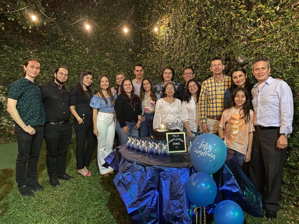 Celebración del equipo de DOMUZ en un jardín, con globos azules y torta