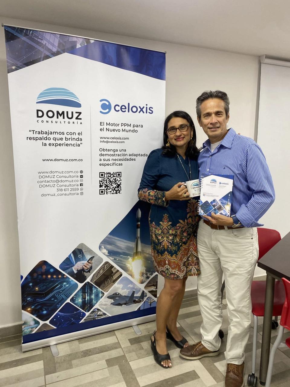 Dos integrantes de DOMUZ junto al pendón de DOMUZ y Celoxis