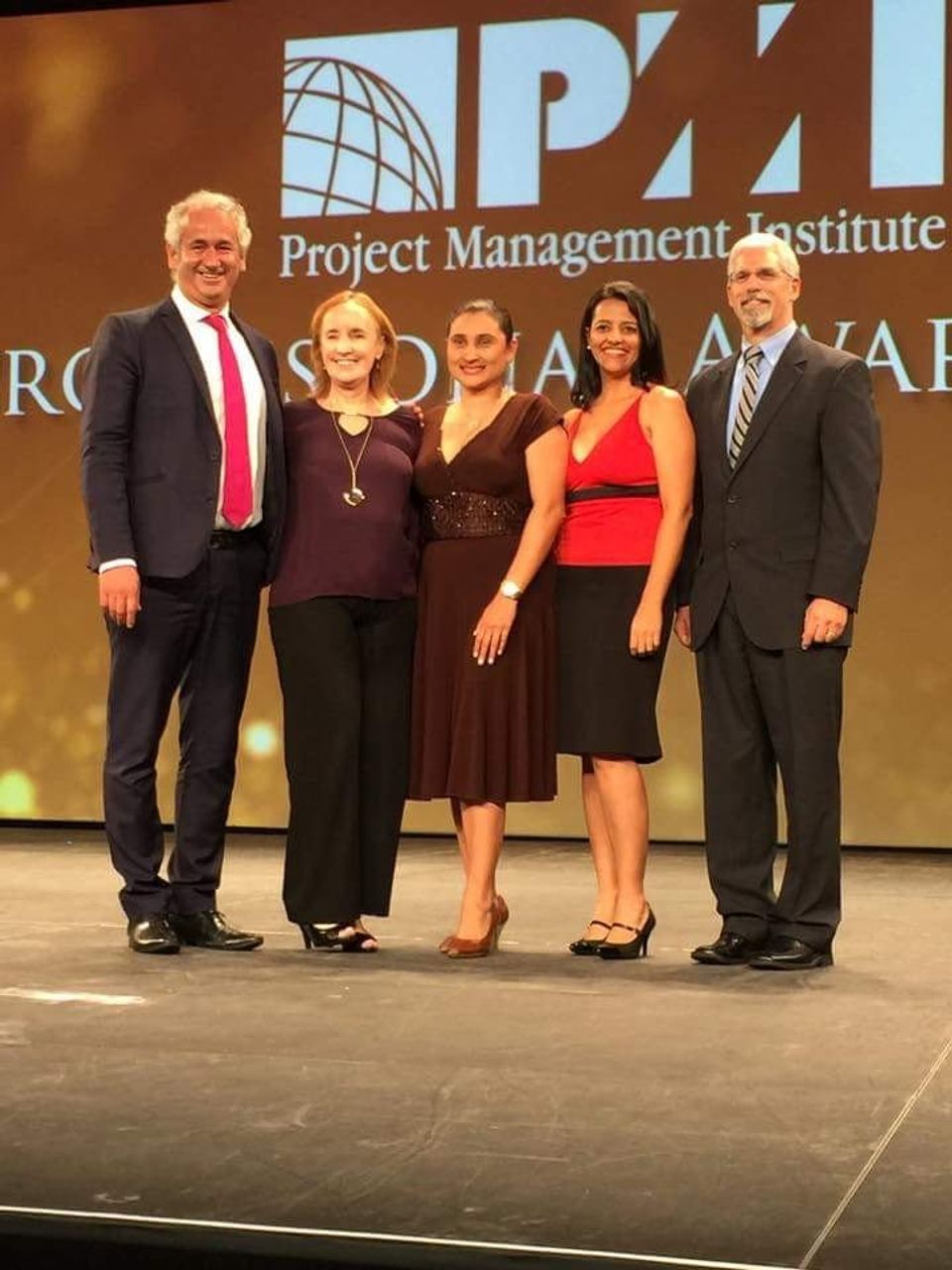 Grupo de directivos en el escenario de un evento del PMI