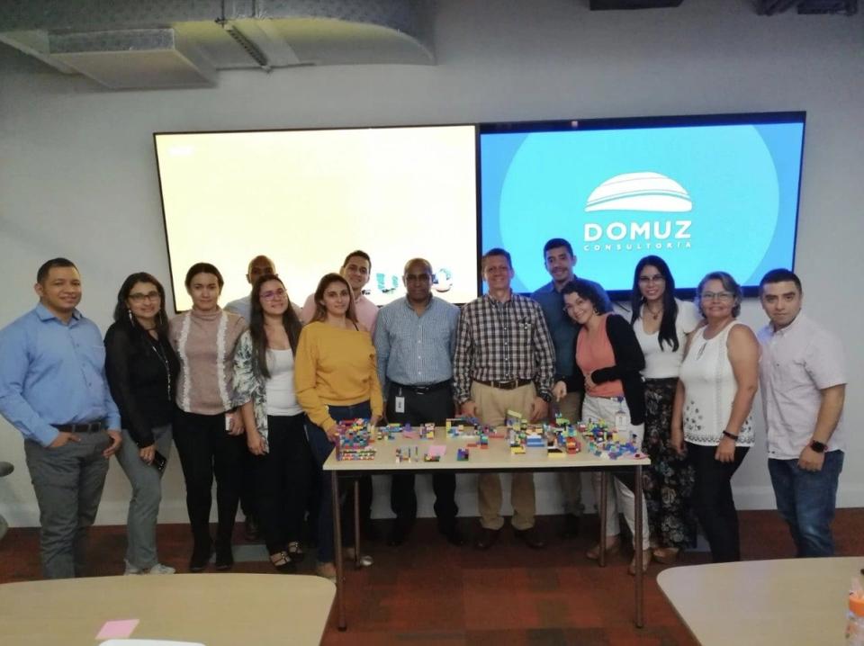 Grupo de asistentes a un taller de DOMUZ frente a la pantalla con el logo de la empresa