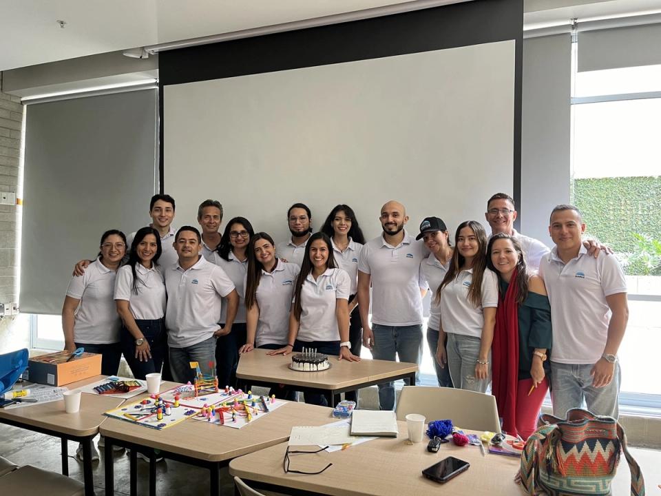 Equipo de DOMUZ con camisetas de la marca en un salón de capacitación, con las maquetas del taller sobre la mesa