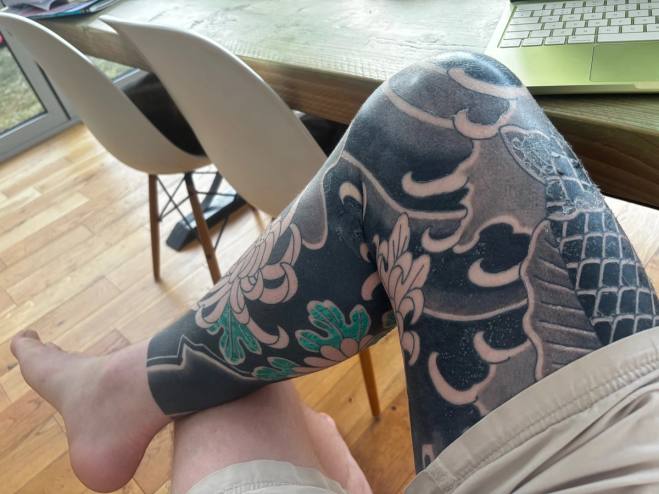 Right leg crossed at the table, healed background and green chrysanthemum leaves on the shin