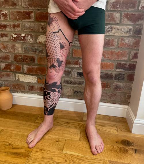 Right leg at home after the back-to-back: koi outline on the thigh, black background below the knee