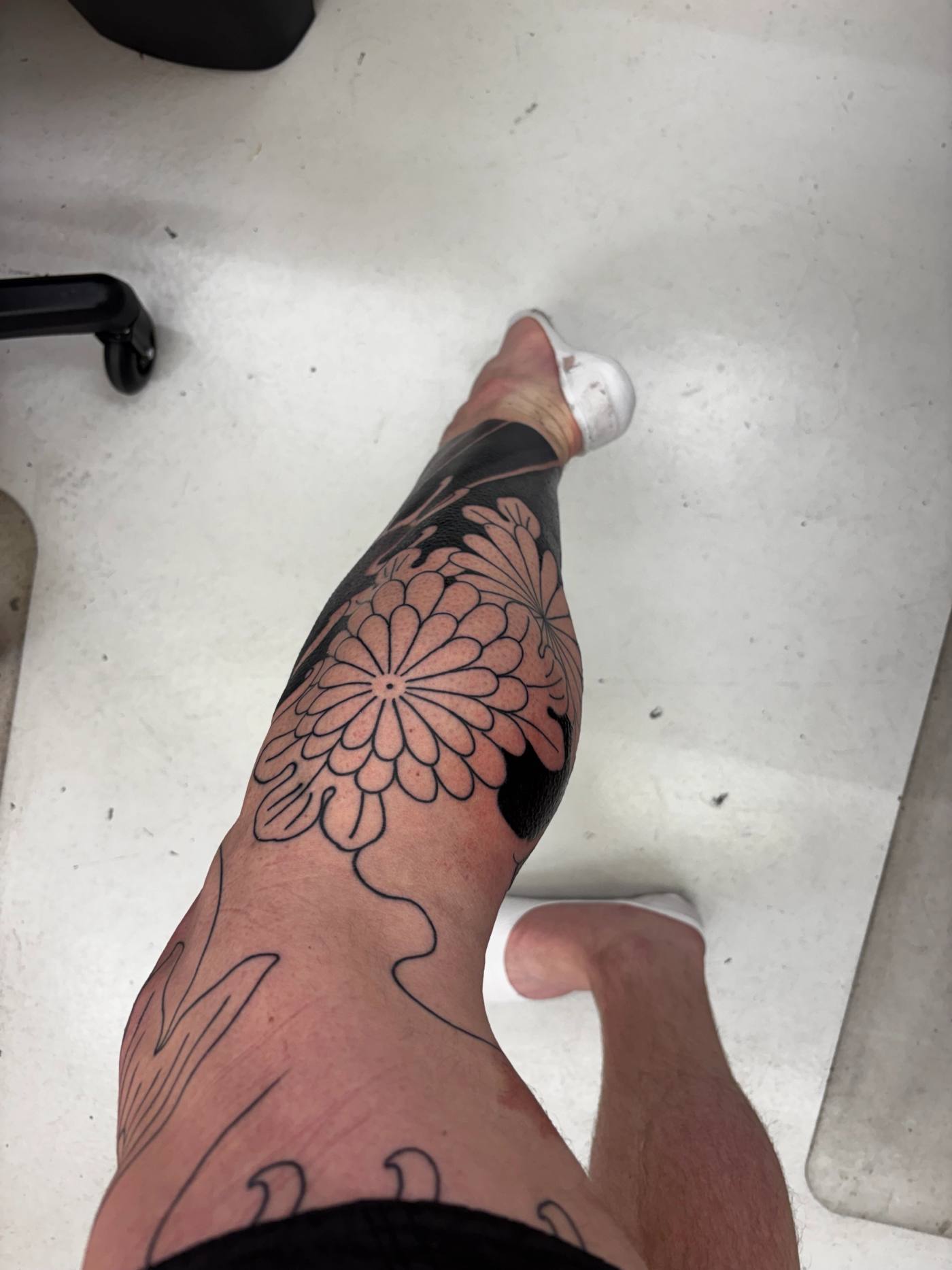 Looking down the right leg from the chair after day one, chrysanthemum outline and black below the knee