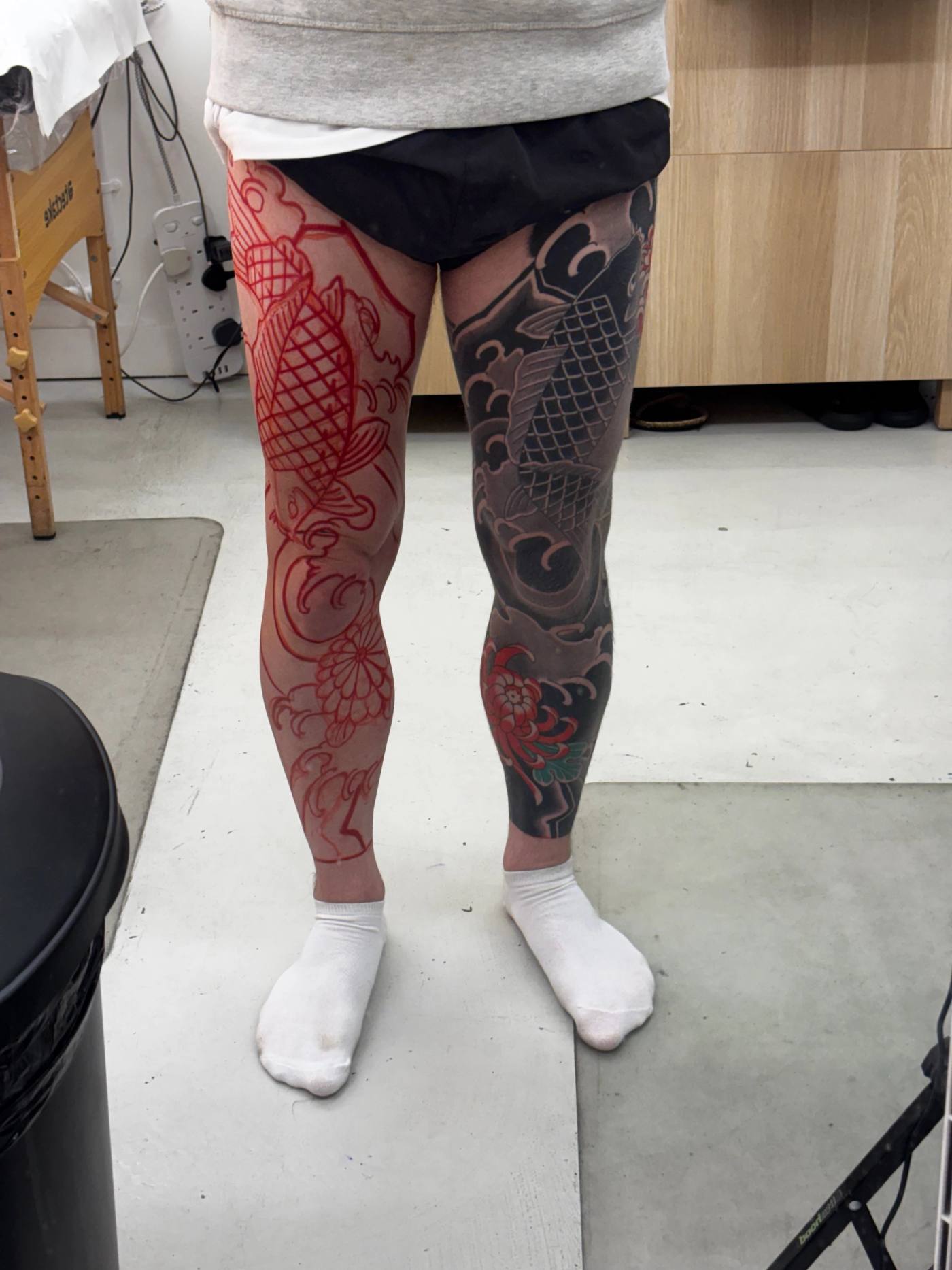 Both legs in the studio: the left drawn up in red stencil, the finished right leg beside it