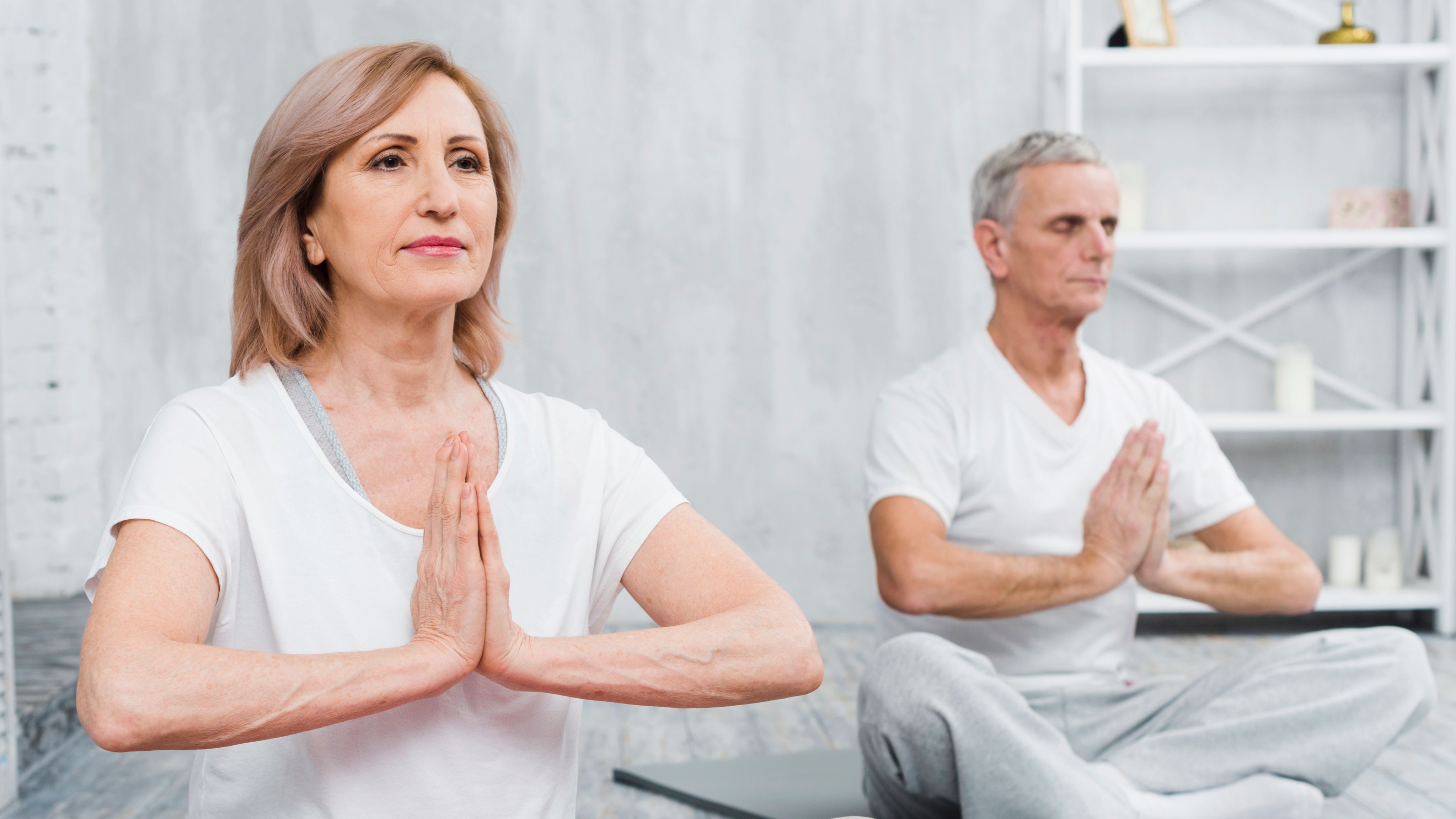 Healthy senior couple practicing meditation and mindful breathing indoors, promoting stress reduction, healthy aging, emotional wellness, and balanced lifestyle habits