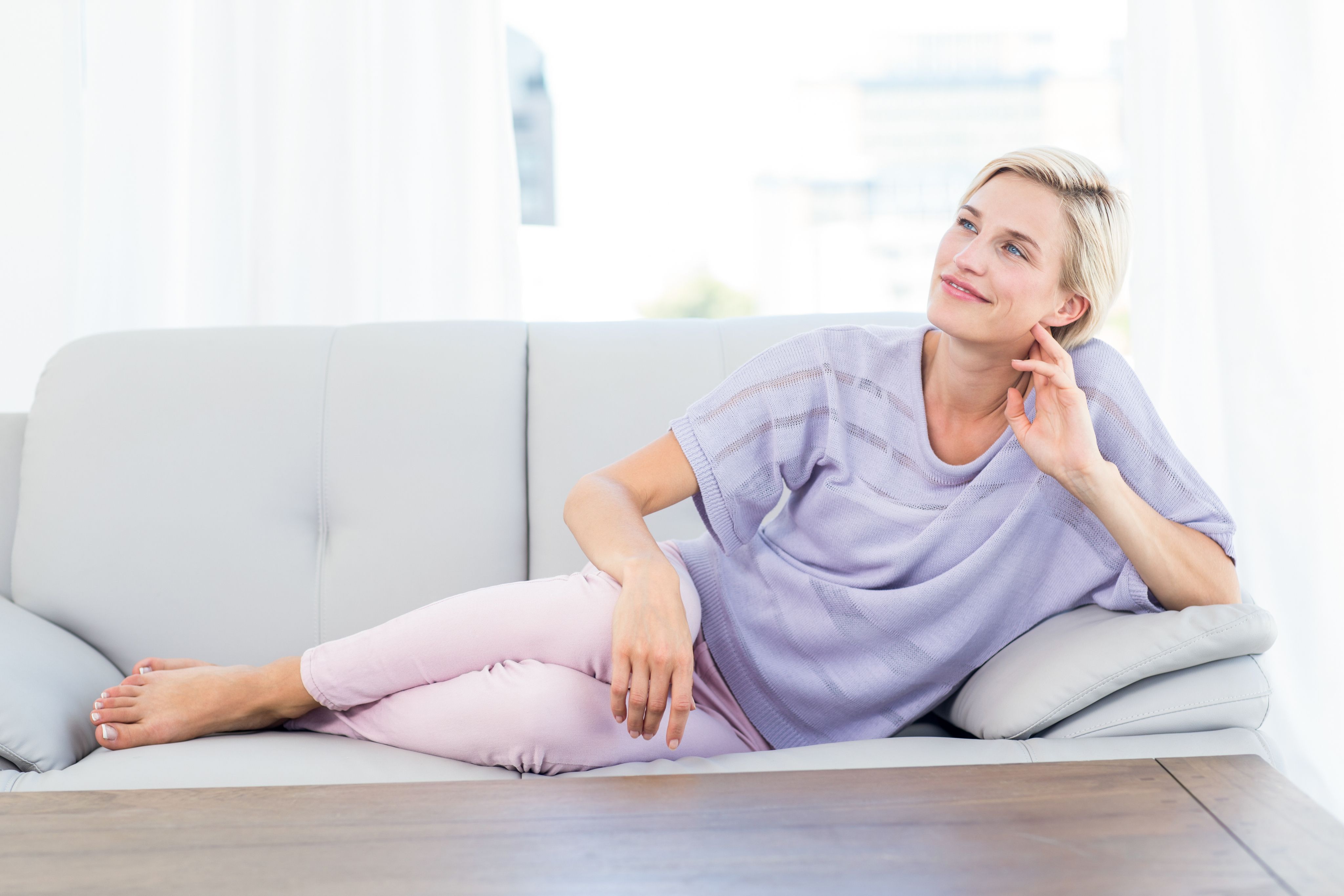 Woman relaxing on sofa in bright living room.