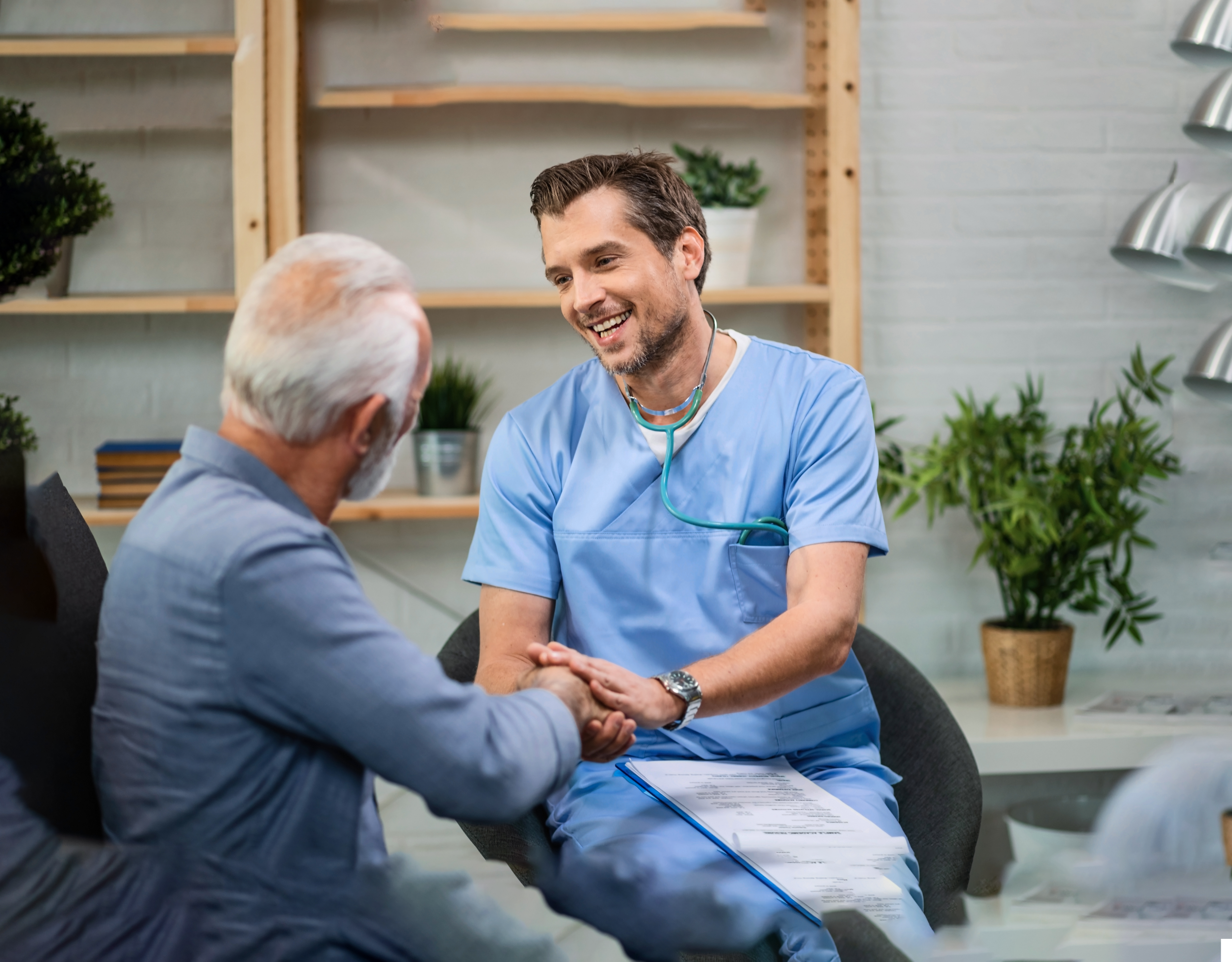 Healthcare provider shaking hands with a patient during an in-person medical consultation