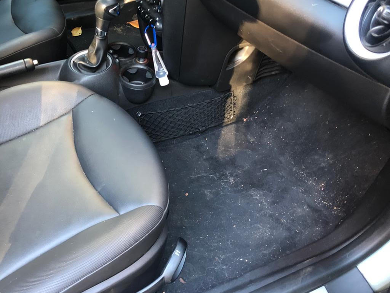 Vehicle interior before mobile-detail prep with personal items and loose trash still inside the cabin
