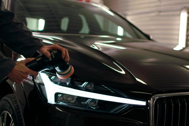Craftsman doing a headlight restoration car detail. 