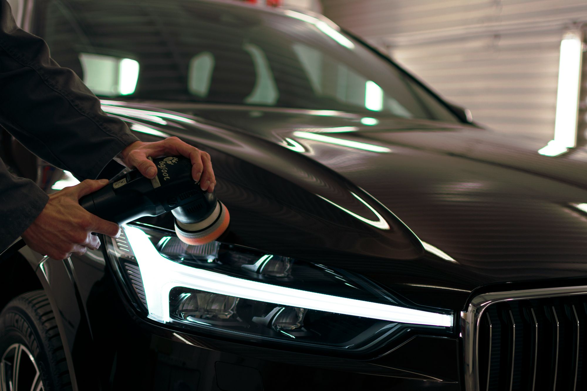 Craftsman doing a headlight restoration car detail.