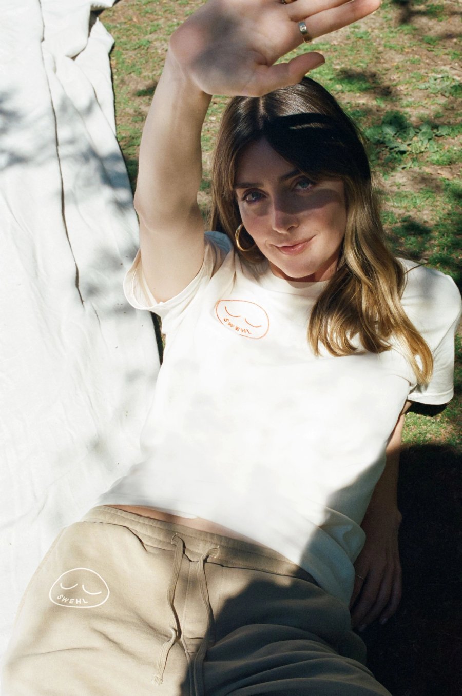 a woman sitting on the ground holding her hand up