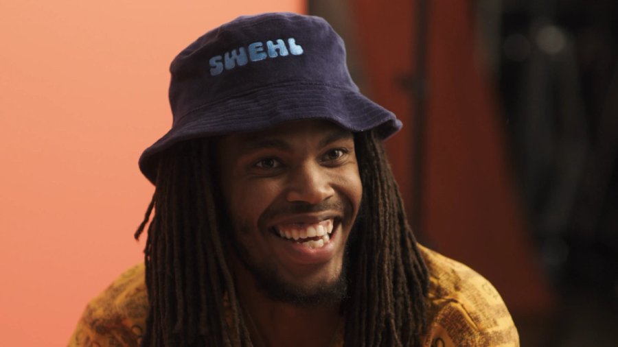 a man with dreadlocks wearing a purple hat