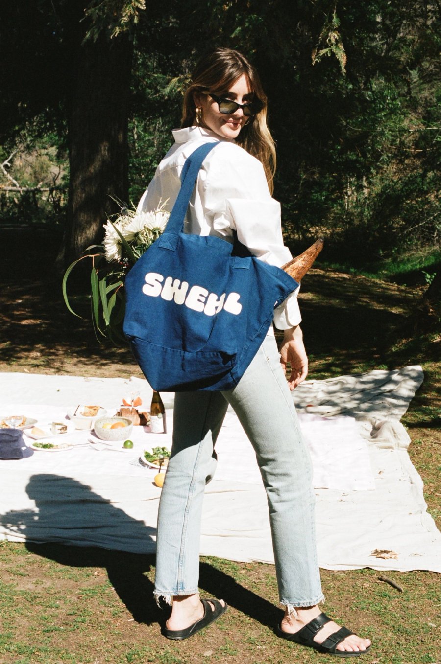 a woman carrying a blue tote bag and flowers