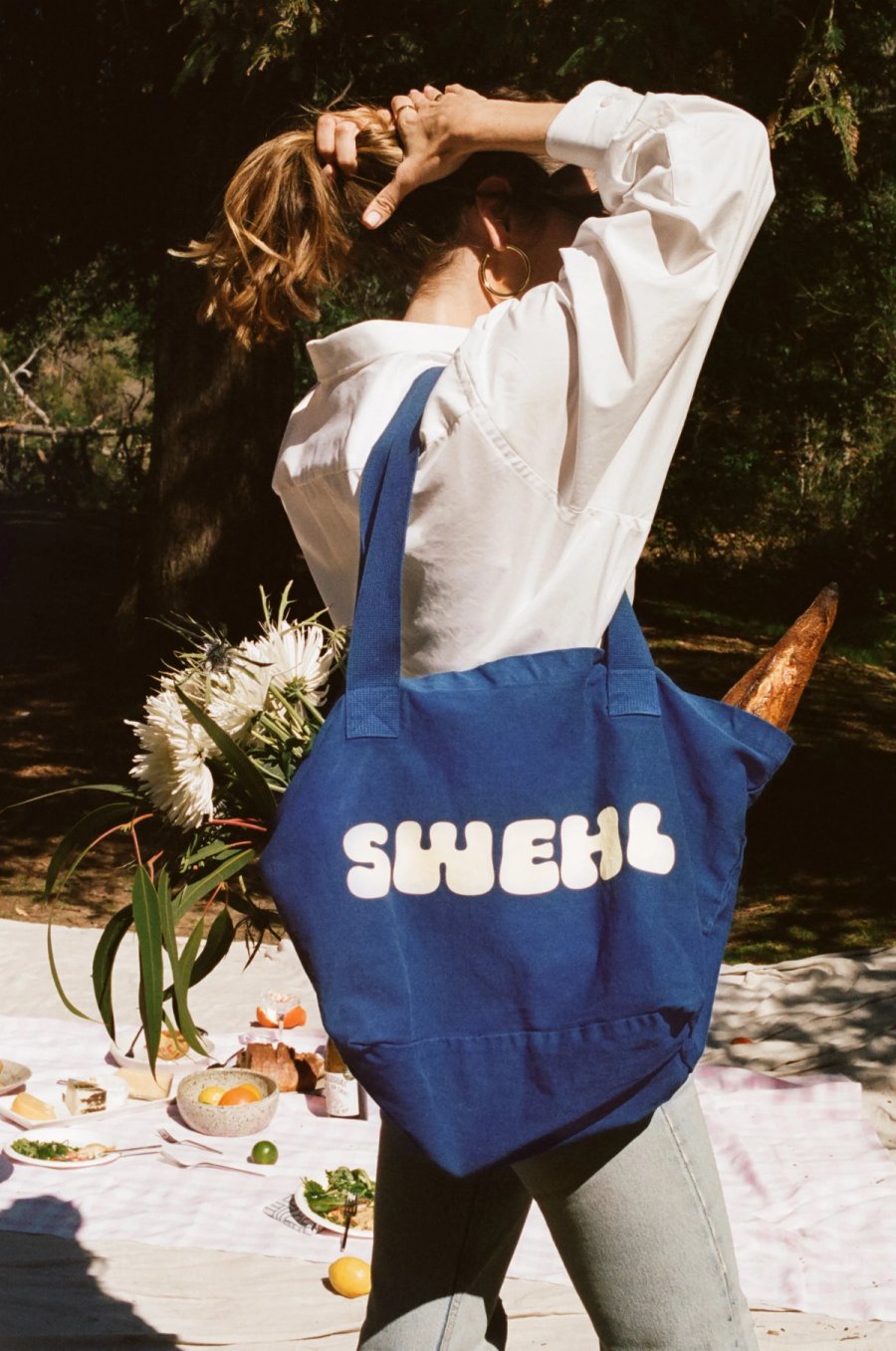 a woman carrying a blue tote bag over her head