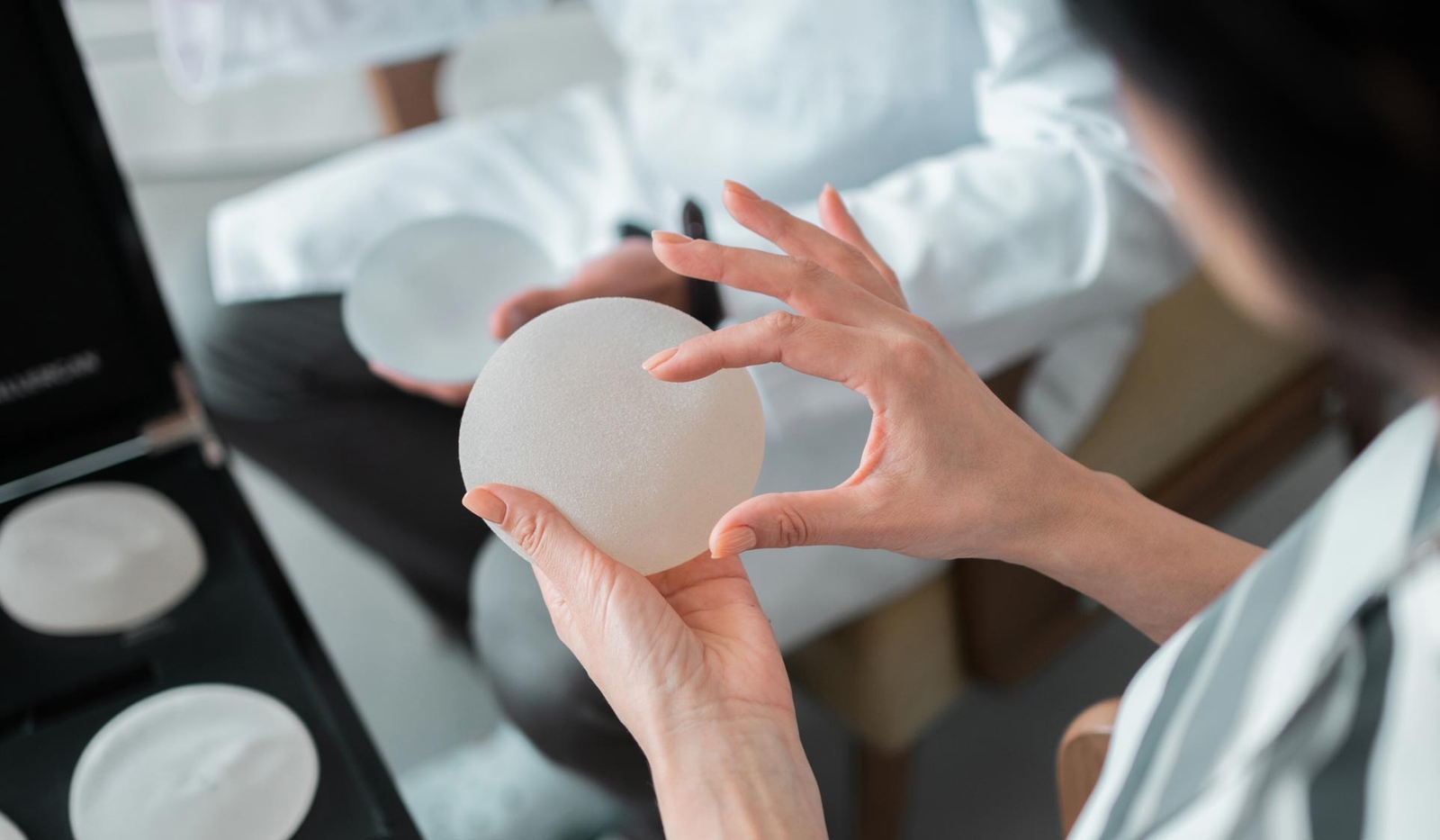 Woman inspecting breast implant in her hand