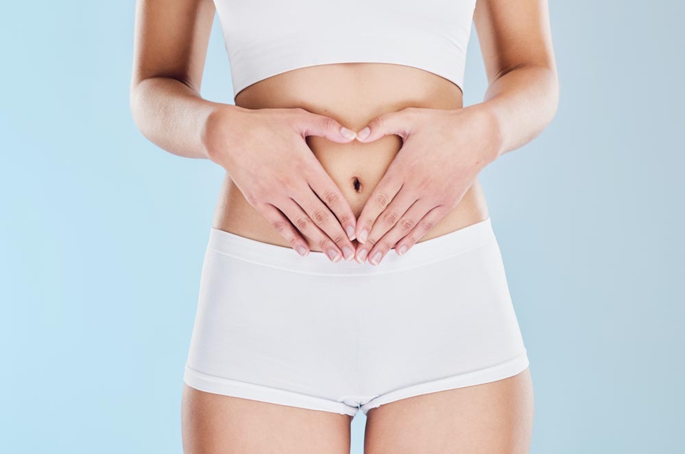 Woman holding her abdomen with her hands in the shape of a heart