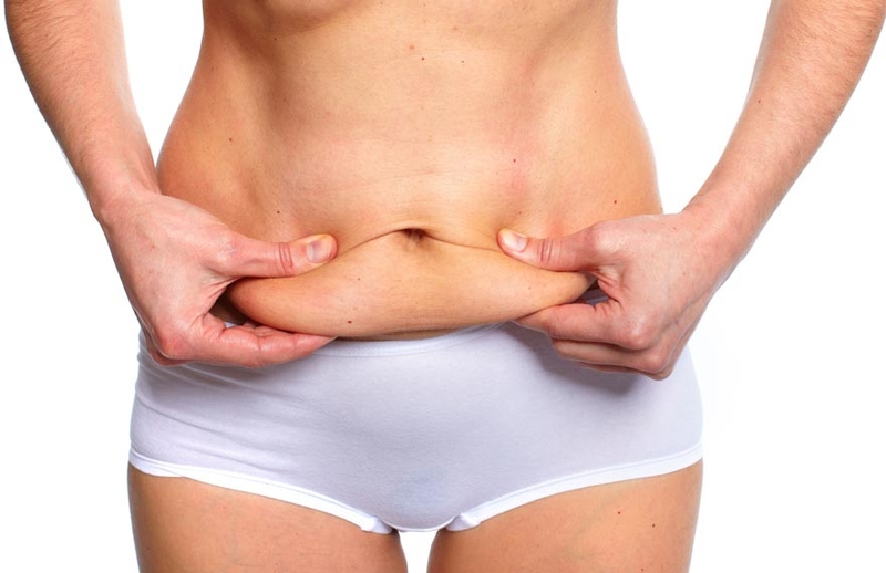 Woman holding excess fat on abdomen