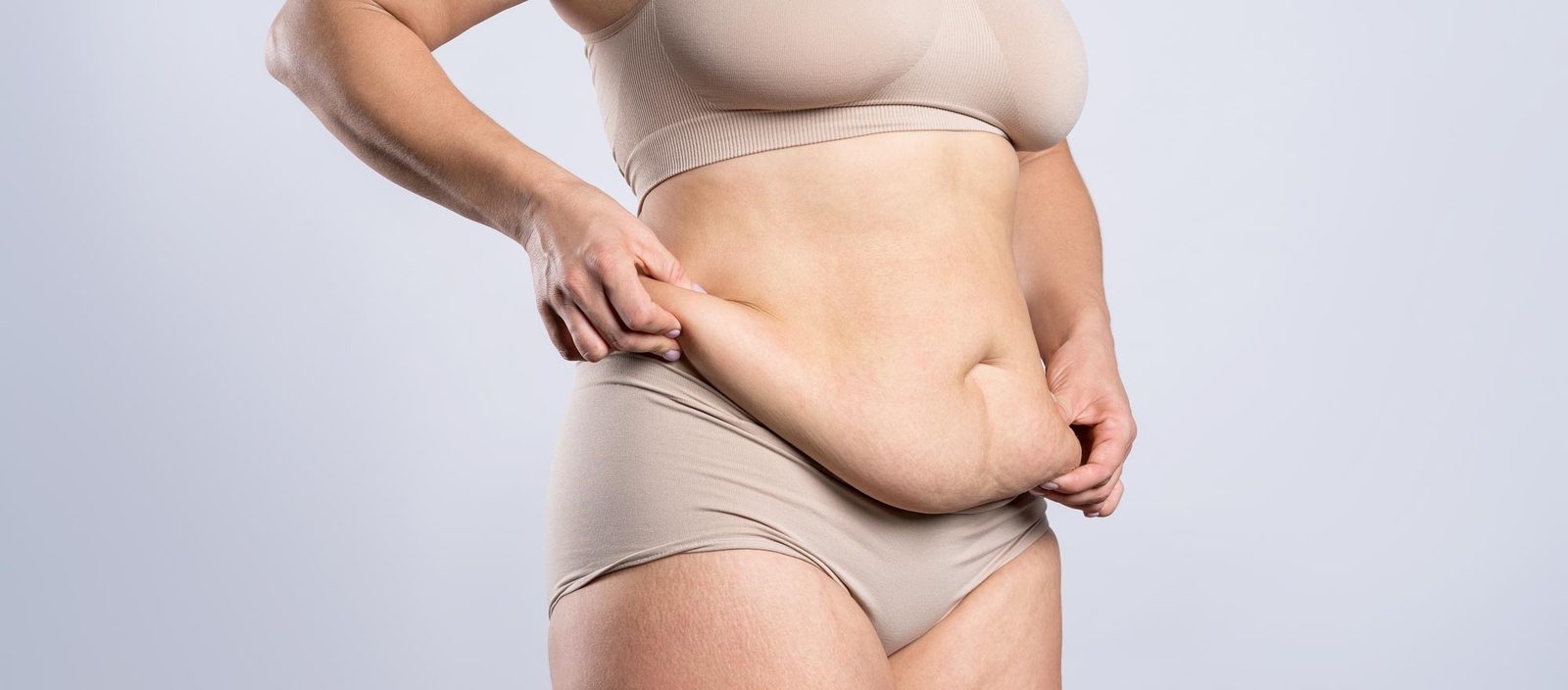 Woman holding excess fat on abdomen