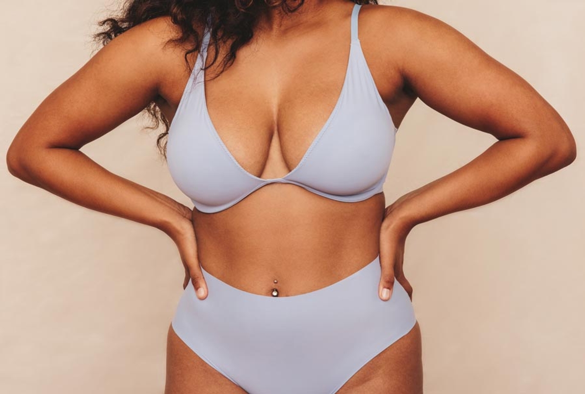 Woman in grey undergarments posing with hands on hips