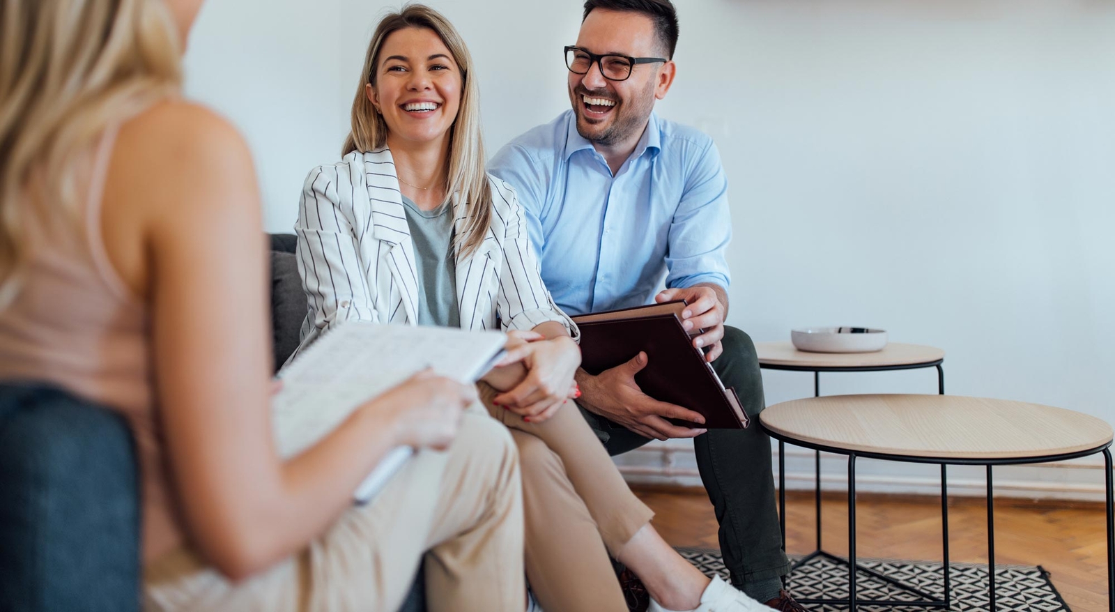 Woman and man laughing talking to another woman