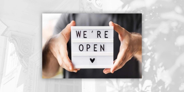 Man holding a sign that says "We're open" with a heart