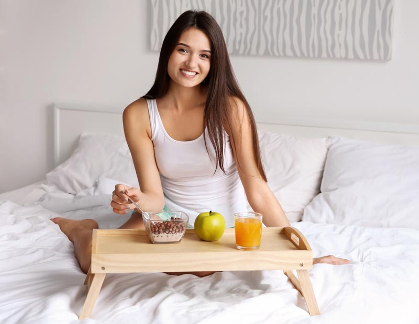 Woman enjoying breakfast in bed smiling