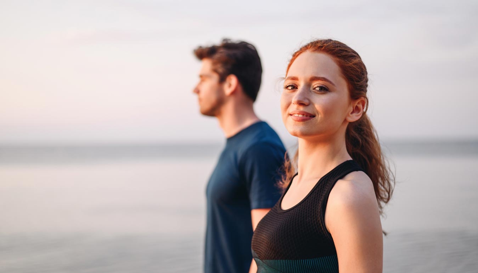Smiling woman in black athletic top on the beach at sunset