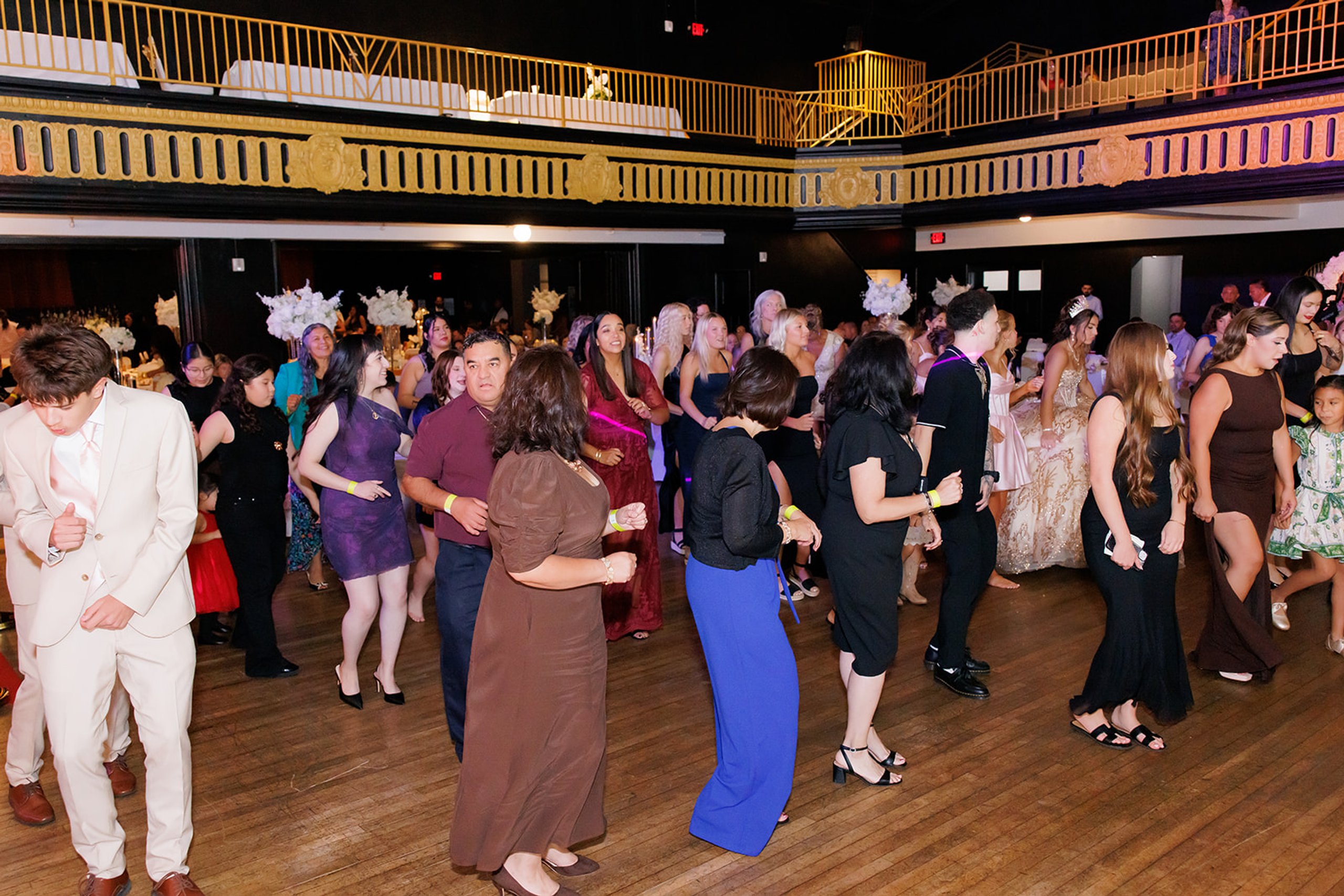 Invitados de todas las edades bailando juntos por el salón en una quinceañera en Admiral Theater, Omaha