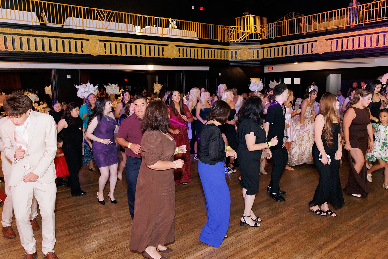 Invitados de todas las edades bailando juntos por el salón en una quinceañera en Admiral Theater, Omaha