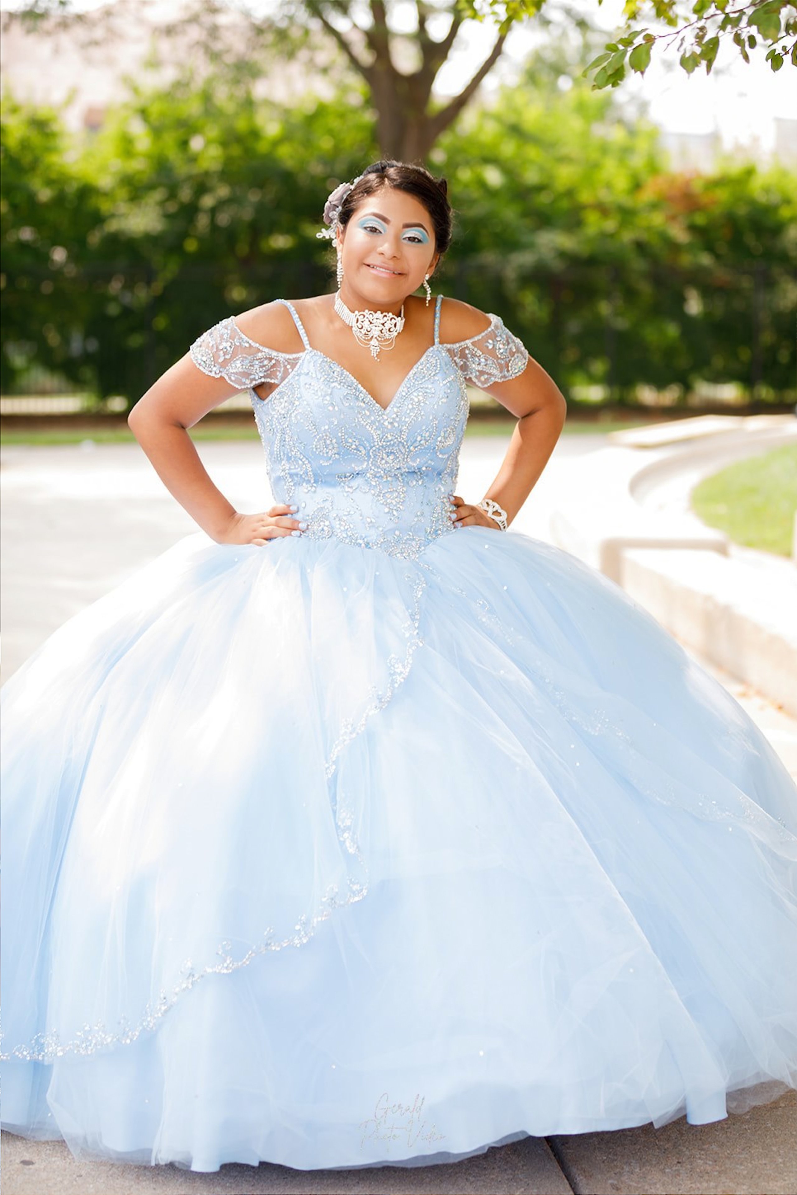 Quinceañera in a layered light blue tulle ball gown posing outdoors, Omaha XV años portrait