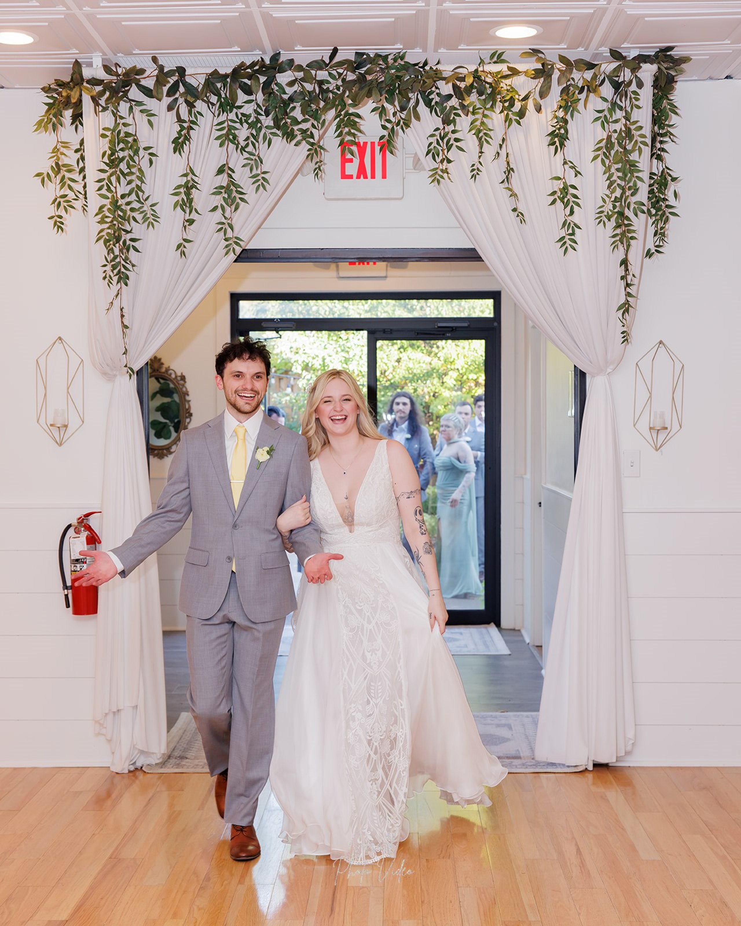Logan and John making their grand entrance through an ivy draped doorway at their Omaha wedding reception