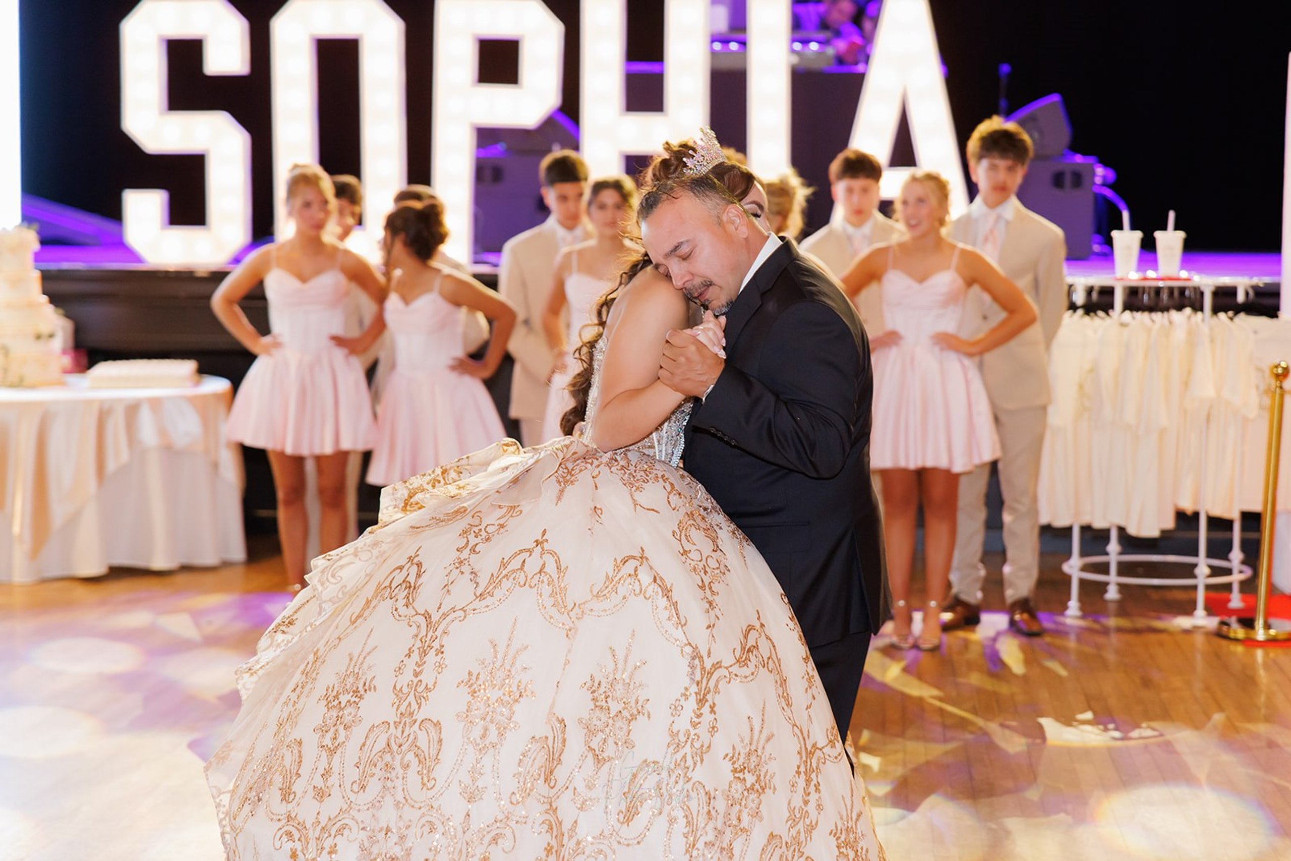 Sophia bailando con su papá, apoyando la cabeza en su hombro frente a su corte en Admiral Theater, Omaha