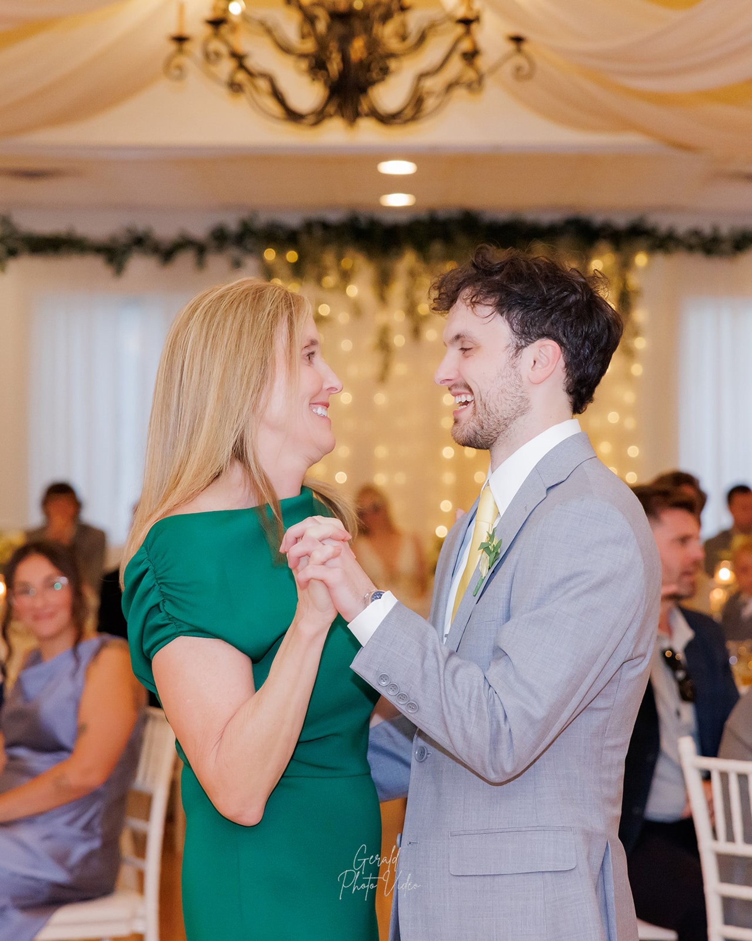 Groom dancing with his mother in an emerald green dress at his wedding reception