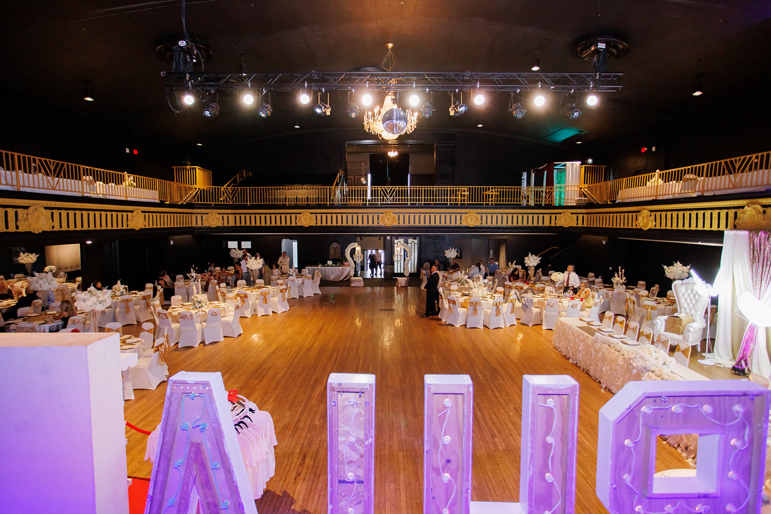 Vista amplia de la pista de baile, las mesas y las letras iluminadas en una quinceañera en Admiral Theater, Omaha
