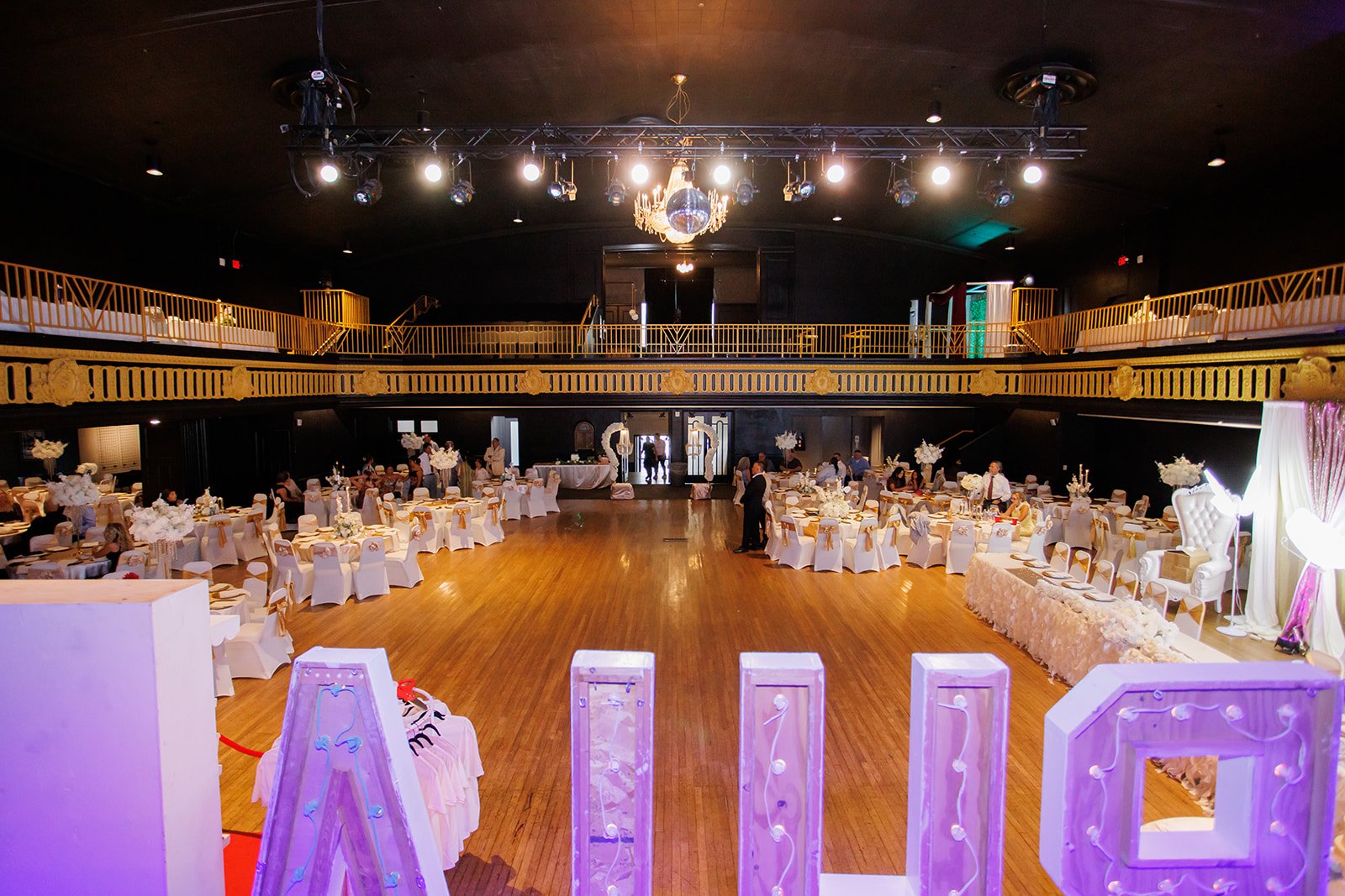 Vista amplia de la pista de baile, las mesas y las letras iluminadas en una quinceañera en Admiral Theater, Omaha