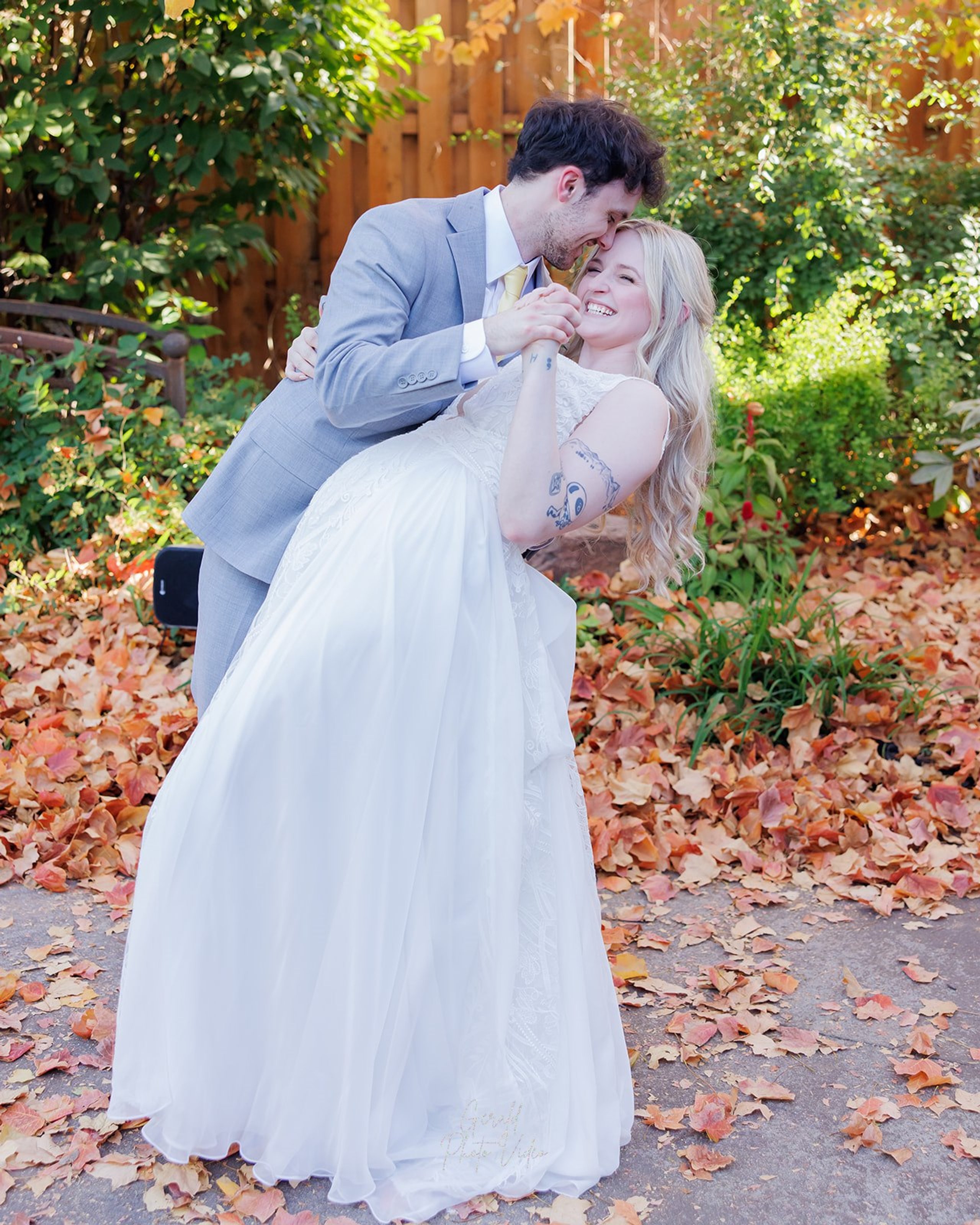 Groom dipping the bride for a kiss among red and orange autumn leaves at The Arbor Event Venue, Omaha