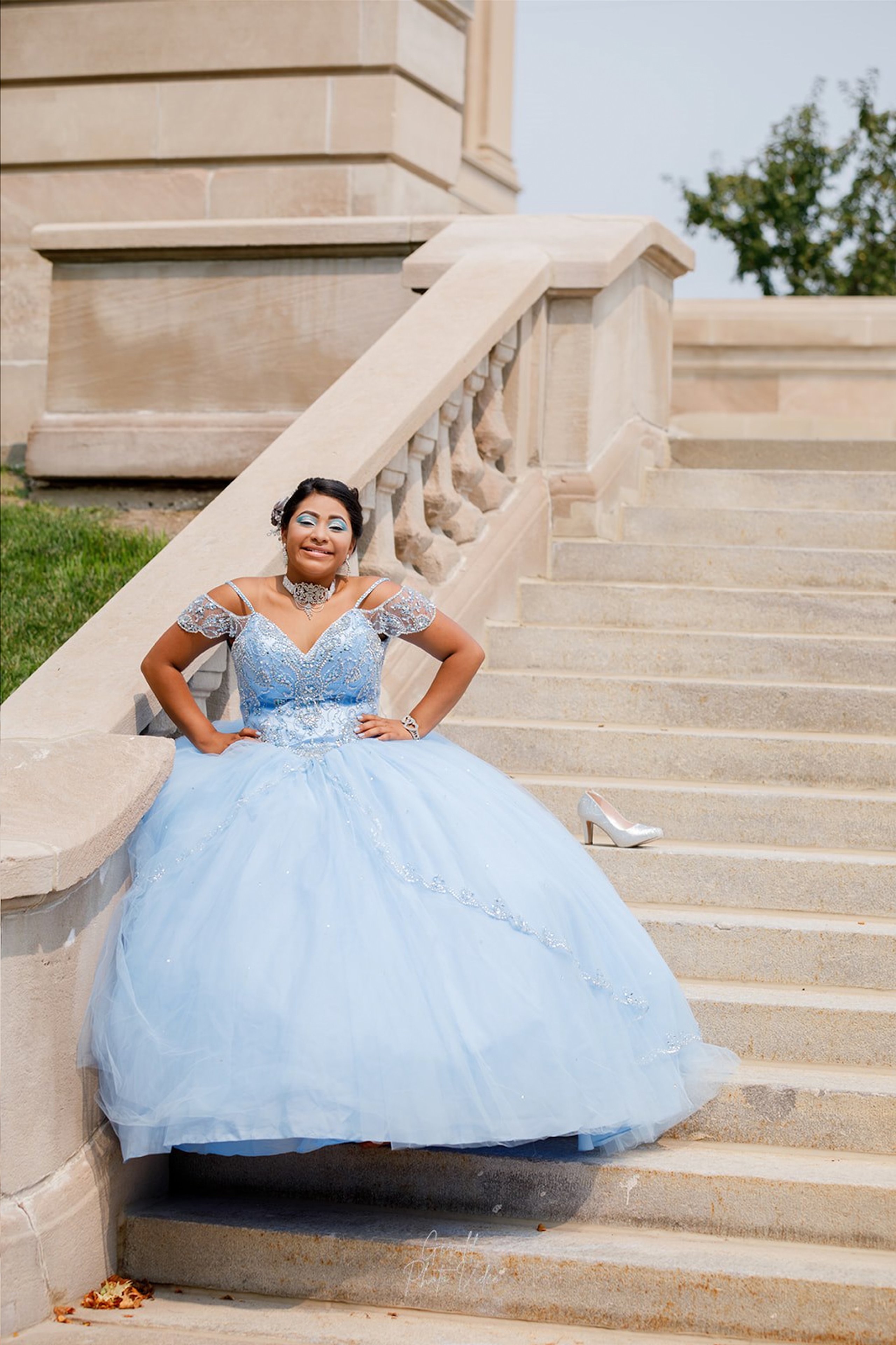 Quinceañera in a blue gown seated on historic stone steps, Nebraska quinceañera photographer Gerald Photo Video