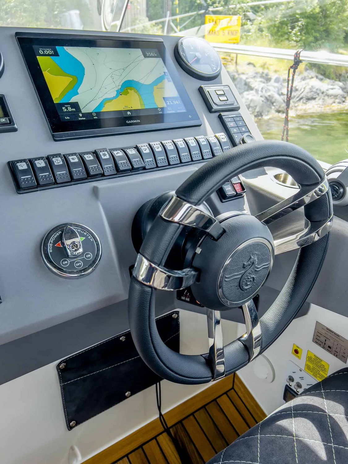 View of the helm station on the Marex 310 Sun Cruiser motor yacht with wheel, Garmin display and switch panel.