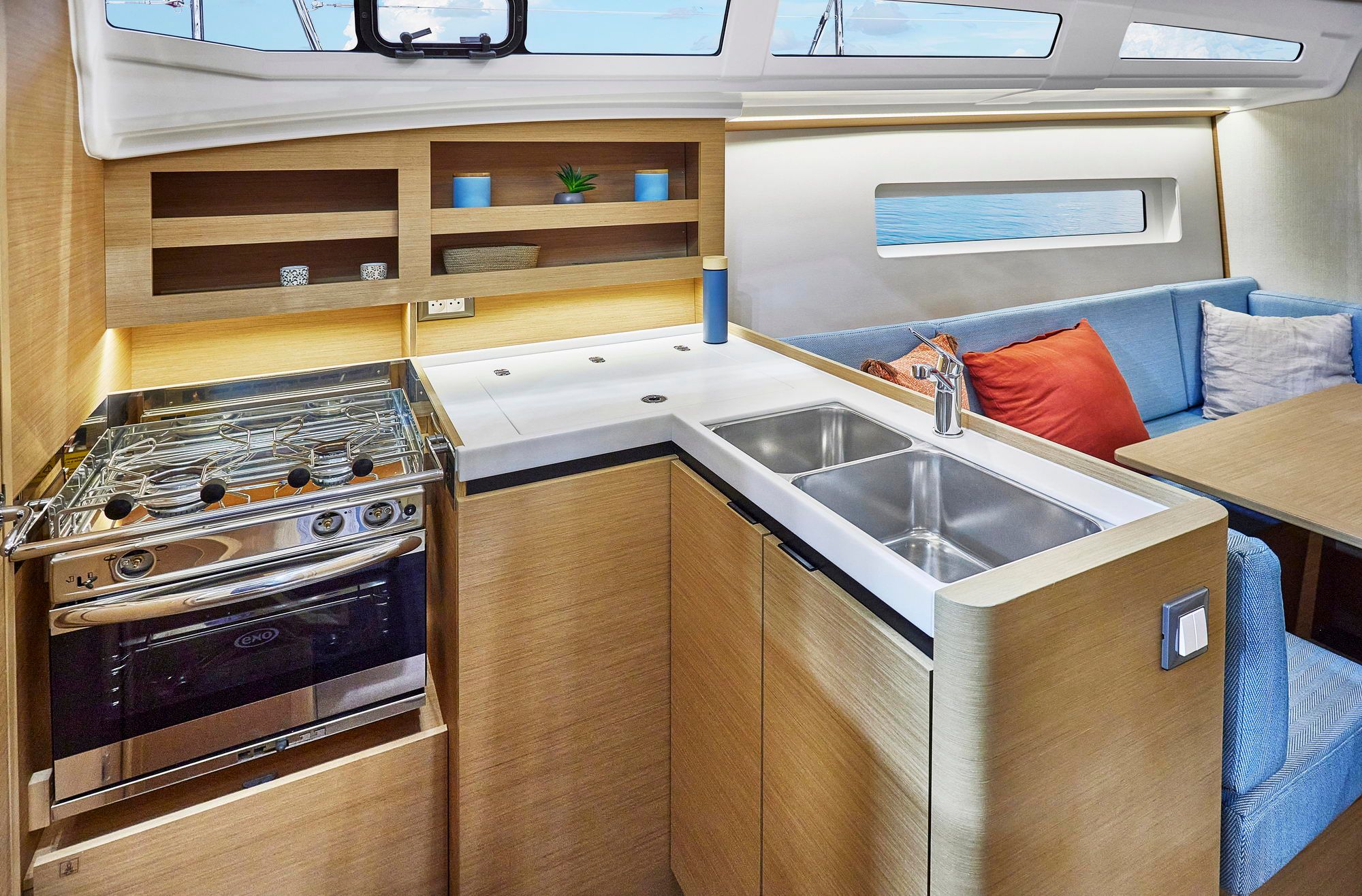 Moderne Kombüse mit Gasherd und Doppelspüle sowie Teil des Salons auf der Jeanneau Sun Odyssey 380.