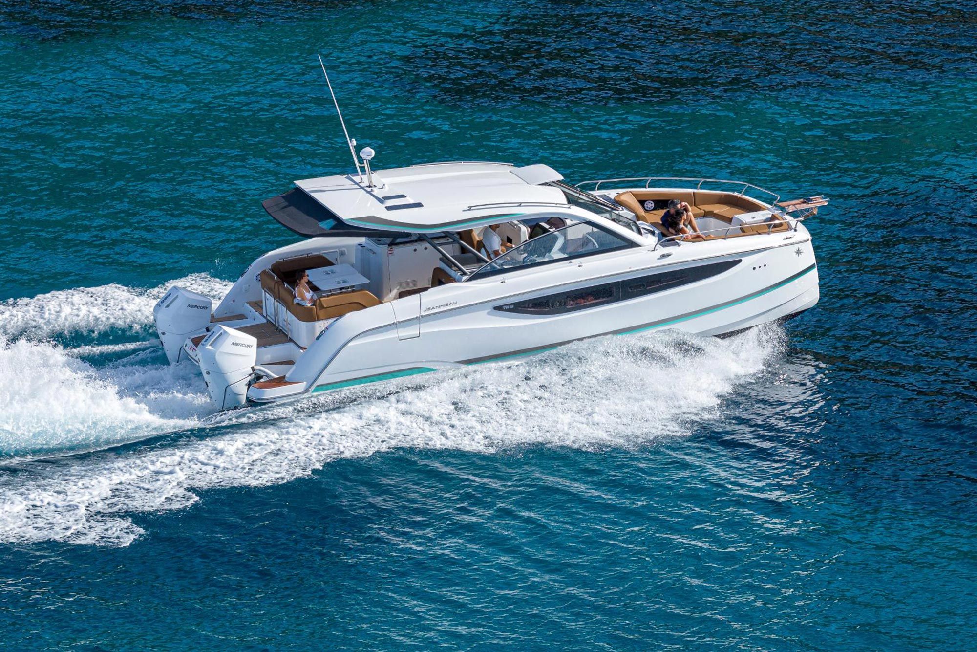 White Jeanneau TH38 motor catamaran with twin outboard engines cruising on turquoise water, with people on board.