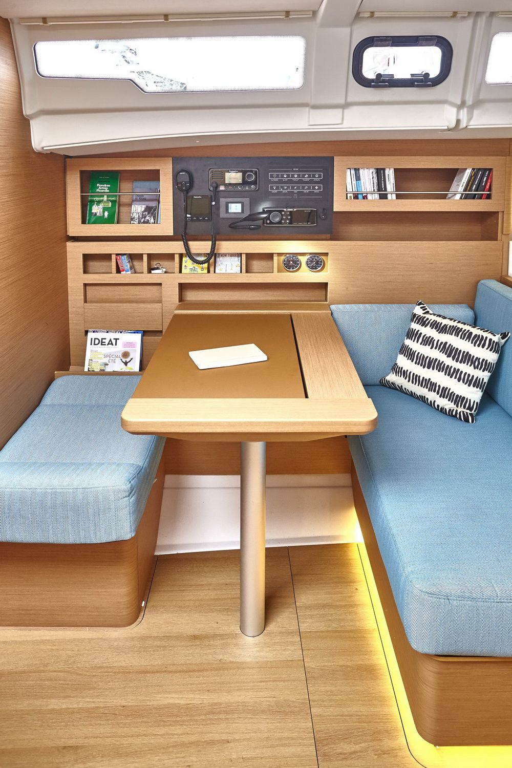 Interior of the Jeanneau Sun Odyssey 490: saloon with blue sofas, wooden table and navigation panel.