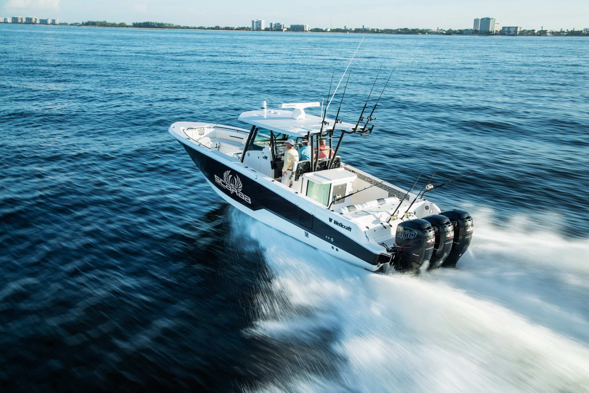 Wellcraft Fisherman 352, ein Angelboot in Fahrt auf dem Wasser, mit drei Außenbordmotoren und Crew an Bord.