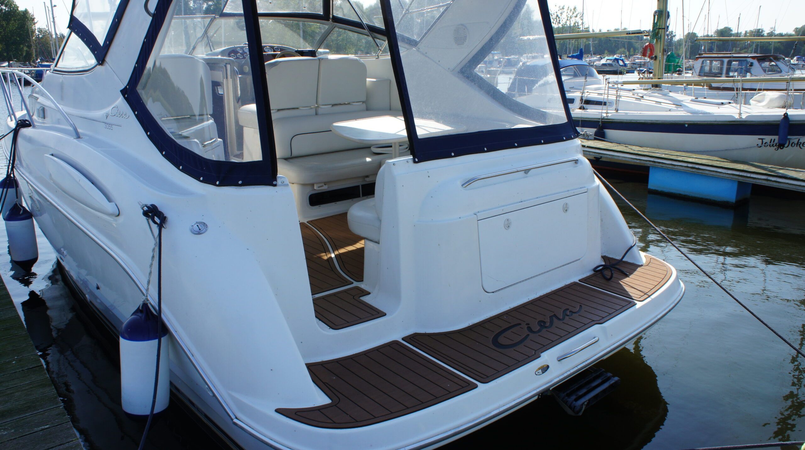 Widok na rufę i kokpit jachtu motorowego Bayliner 3055 Ciera z pokładem NauticDeck i nowym bimini, zacumowanego przy pomoście.