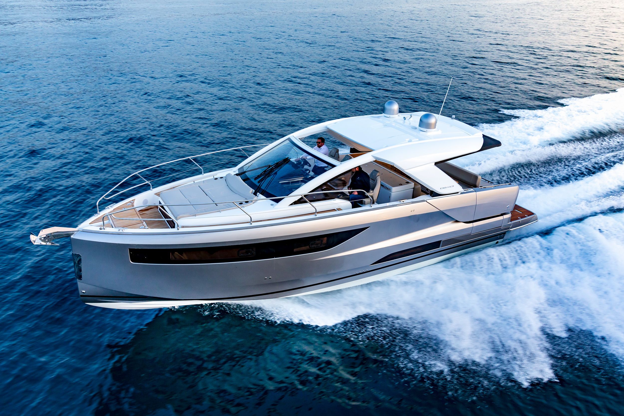 Jeanneau DB/43 IB, a luxury dayboat, cruising on the water, aerial view. Two people on board.