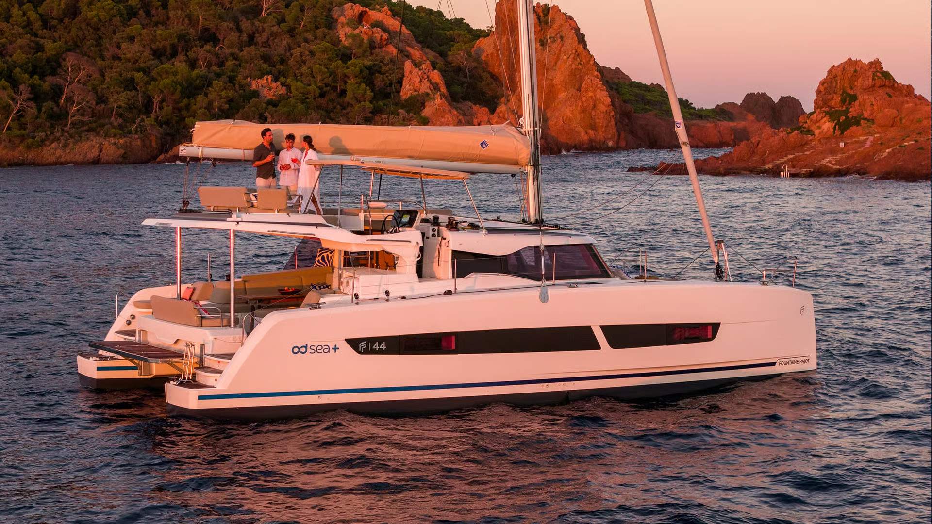 Katamaran Fountaine Pajot FP44 na morzu o zachodzie słońca, z trzema osobami na flybridge.