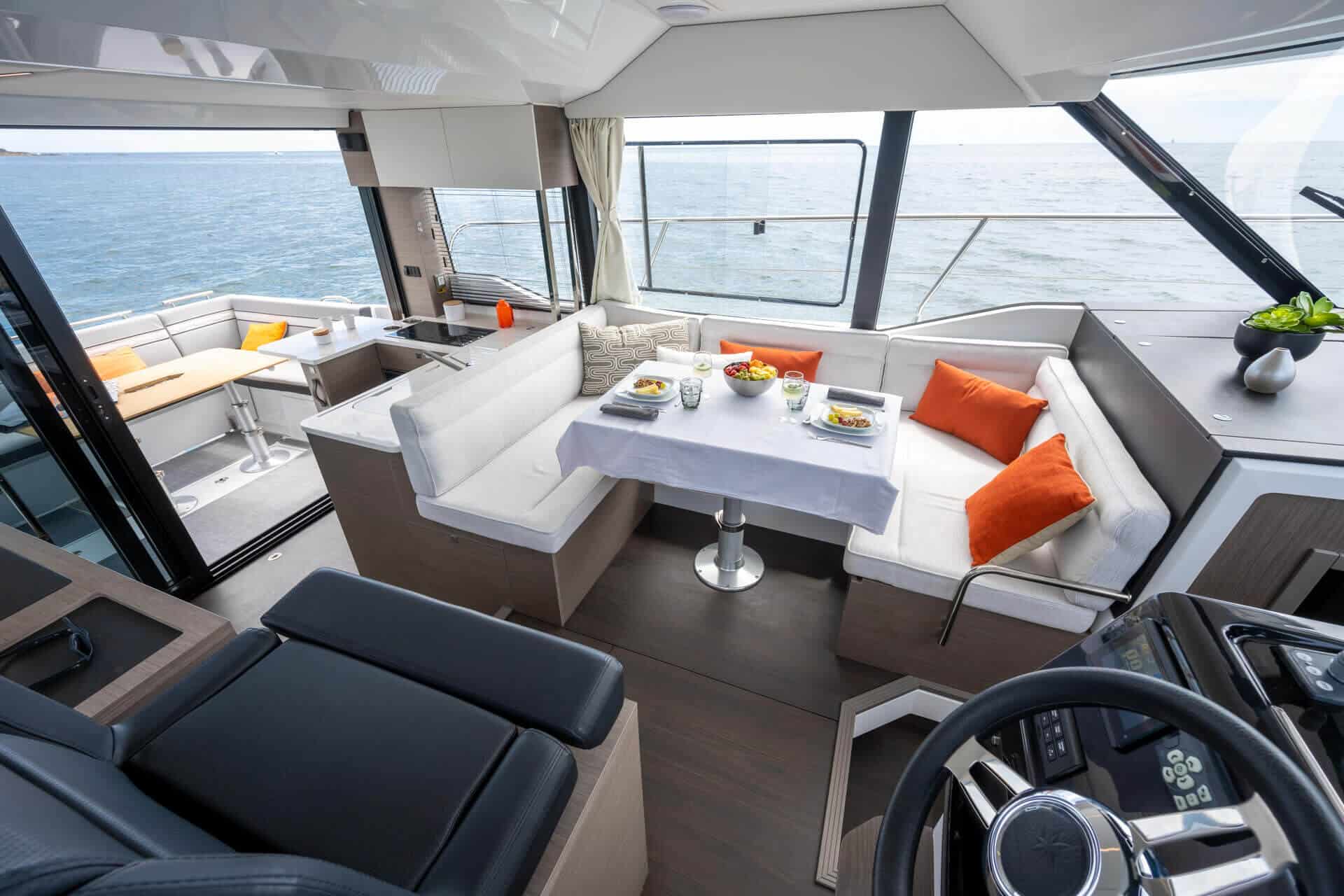 Widok na przestronny salon z jadalnią i sterówkę na jachcie Jeanneau Merry Fisher 1295 Flybridge, z widokiem na morze.